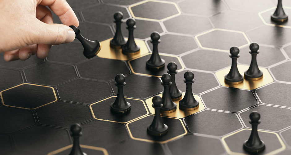 Hand moving a game piece on a board, symbolizing strategic planning and decision-making in building an effective marketing strategy.